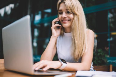 Telefonda konuşan ve dizüstü bilgisayar kullanarak gülümseyen Freelancer