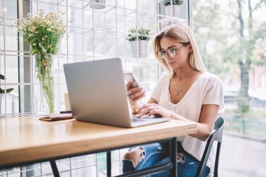 Modern teknolojiler hakkında içerik web blog mesajları kontrol ederken sosyal ağdan takipçisi göz koruma yazarak cevap sağlamak için trendy Gözlük Genç çekici hipster kız