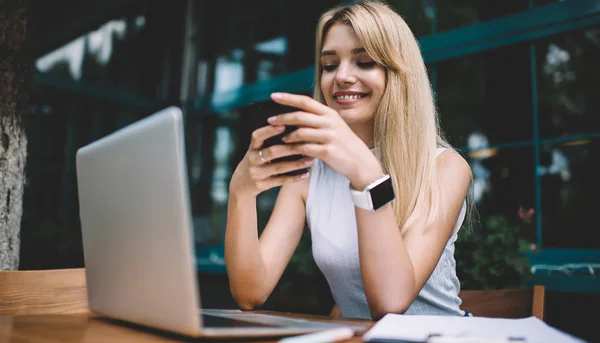Glimlachend freelancer met laptop met smartphone — Stockfoto