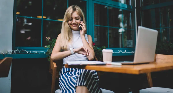 Freelancer hablando por teléfono y comprobando el tiempo — Foto de Stock