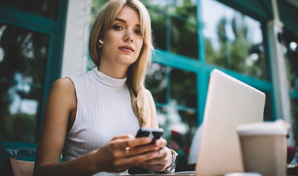 Pekerja lepas perempuan menggunakan smartphone dan melihat ke kamera — Stok Foto