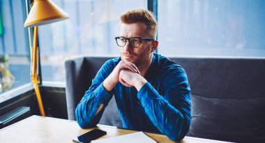 Vizyon düzeltme üniversite projesi için ideo üzerinde düşünme için optik gözlük düşünceli hipster adam, notlar yapmak için ders kitabı ile masaüstünde oturan şık gözlük düşünceli adam