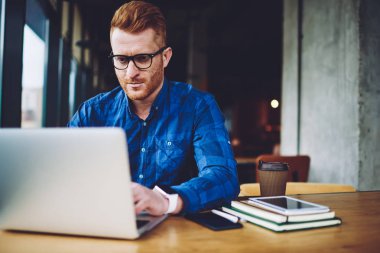 Boş zamanlarında ücretsiz kafeterya wifi bağlı haftalık program düzenlemek için uygulama yüklemek için Kafkas erkek uzaktan işçi yükleme, gözlük okuma ciddi adam meslektaşından mesaj aldı