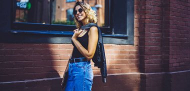 Gün zaman şehir sokakta yürüyüş diş gülümseme ile mutlu genç kadın, el klasör ve ceket ile üniversiteye dönen neşeli kadın öğrenci, sıcak hava zevk başarılı hipster kız