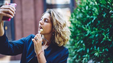 Oyuncu hipster kız dijital akıllı telefon Gadget Modern Web kamera kullanarak sosyal ağda yayın gönderme için komik resimler yapma, cep telefonu üzerinde selfie fotoğrafları tıklayarak neşeli kadın