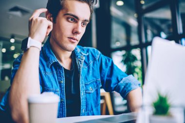 Pensive hipster adam dizüstü bilgisayarda iyi internet bağlantısı kullanarak programlama ve yazılım geliştirme hakkında ciddi web semineri izlerken, sosyal ağlarda siyasi haber okuma adam düşünme