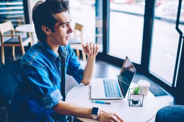 Kahve dükkanı masada modern dizüstü bilgisayar ile oturan Düşünceli hipster adam uzaktan serbest çalışan, düşünceli yetenekli bin yıllık adam rahat kıyafet antivirüs için bildirim üzerinde düşünme