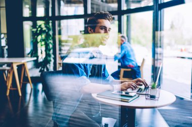 Mutlu erkek yazılım geliştiricisi uzak iş iyi duygu ve web sitesi ile program görevi tamamlandı, pozitif bin yıllık adam gülümseyen ve coworking alanında dizüstü bilgisayar cihazı kullanırken kenara bakarak