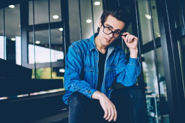 Boş zamanlarında açık havada kameraya bakarak gözleri koruma sağlamak için gözlük yakışıklı hipster adam Portresi, kampüs merdivenlerinde poz denim kıyafeti giymiş genç beyaz erkek genç