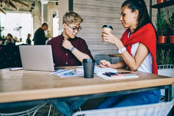 Collaboration of asian hipster students on development new design for website spending time in modern coworking space,chinese young man and woman studying in coffee shop sitting at desktop with laptop