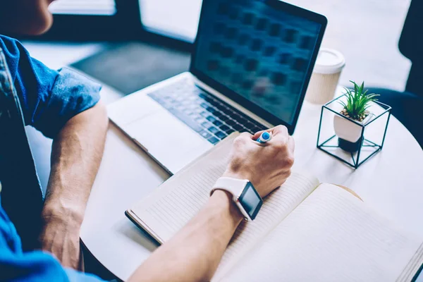 Netbook ile kahve dükkanı masada öğrenirken ders kitabında bilgi yazma erkek ellerin geri görünümü kırpılmış, dizüstü bilgisayar üzerinden web sitesinde online websemineri üzerinden öğrenme bin yıllık adam freelancer öğrenme