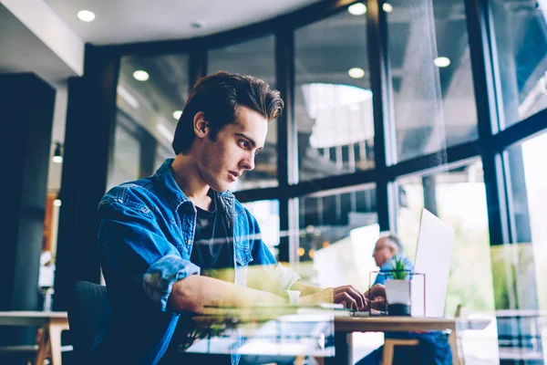 Ciddi erkek o profesyonel dizüstü bilgisayarda internet online dersleri kullanarak programlama için yeni bir dil öğrenme konsantre, adam netbook üzerinde ekran koruyucu değiştirmek için medya dosyalarını indirme