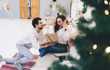 Mutlu, neşeli, beyaz bir kadın, güzel bir kocadan Noel arifesinde hediyelerle heyecanlanıyor. Genç bir hippi, karısına hediye paketi veriyor.