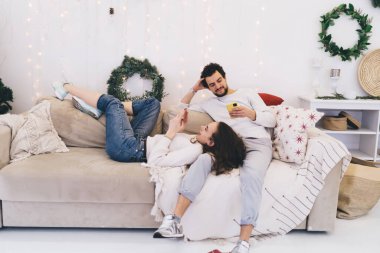 Gülümseyen milenyum yeniyetme kız ve erkek hafta sonları evde dinlenirken iletişimi görmezden geliyorlar. Aletlere ve sosyal ağlara bağımlı çiftler sessiz kalıyorlar.