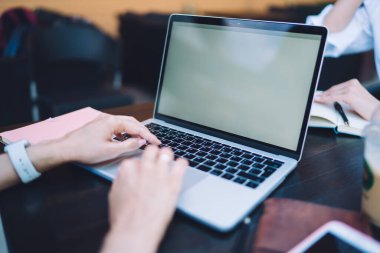 İnternette boş ekranlı dizüstü bilgisayar kullanarak çalışan isimsiz bir kadın. Kafede iş arkadaşıyla oturup planlama yaparken.