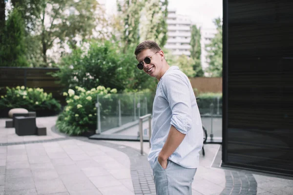 Gündelik giysiler ve güneş gözlüğü takan mutlu bir erkek öğleden sonra çalılarla dolup taşan toprak yığını üzerinde el ele duruyor.