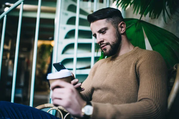 Focused Young Bearded Man Using Smartphone Searching Information While Drinking — Stock Photo, Image