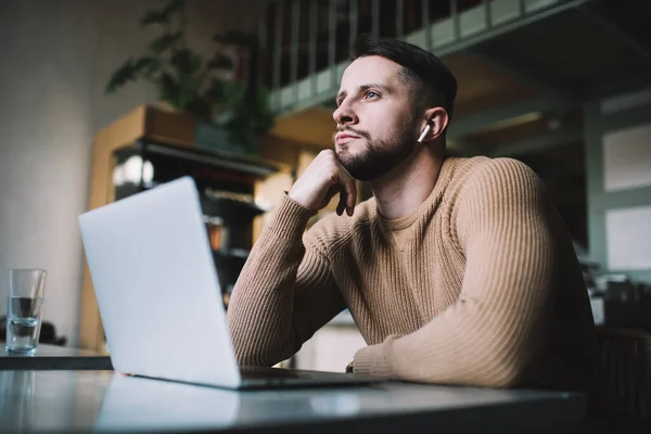 Vousatý Pohledný Chlap Sluchátky Sedí Moderní Kavárně Laptopem Drží Bradu — Stock fotografie