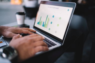 Kurumsal stratejiyi analiz etmek için modern dizüstü bilgisayarda gösterilen gelir grafiklerini analiz eden erkek patron, uygulamayla veri düzenlemek için iş adamlarının bilgi grafiklerini tarıyor