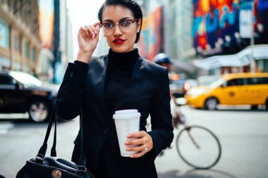 New York 'ta arabaların ve bisikletçilerin doldurduğu yolda elinde meşrubatla duran el çantasıyla güzel bir girişimci.