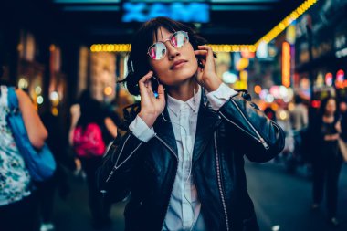 Moda bardakları ve modern kulaklıklarla güzel bir bayan milenyumu. Müzik podcast 'i, elektronik ekipmanlı sakin bir kadın. Metropolitan caddesinde dinlenen huzurlu müzik listesi.