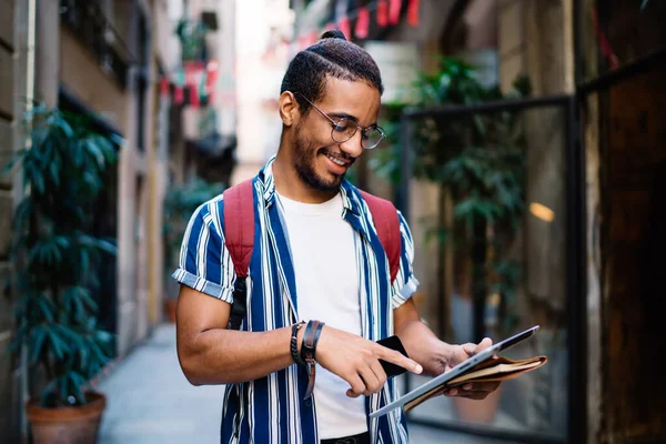 視力補正のためのアイウェアの暗い肌の男性の笑顔旅行中に通りを散歩情報を検索します 肯定的なアフリカ系アメリカ人ヒップスター男ローミングで4G接続を使用してメッセージを送信 — ストック写真