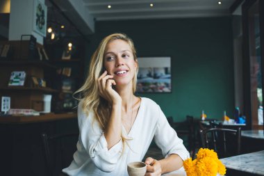 Roma 'daki çağdaş kahve dükkanının bulanık içkisine karşı masada oturup lezzetli sıcak içecekler içerken zarif elbiseli, neşeli ve dalgın bir kadın gülümsüyor.
