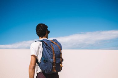 Afrika 'daki ölüm kumlu vadiyi keşfeden erkek turistin arka planda tatil yaparken sırt çantasıyla manzara ufkuna bakan adam yerleşim olmayan doğa ortamını ziyaret ediyor.