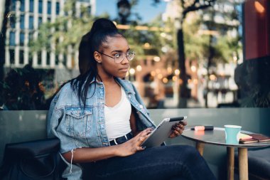 Bilgi ve gezinti için dijital tablet kullanan koyu tenli bir kız öğrenci, 4G bağlantısı üzerinden e-posta ve mesajları kontrol eden genç ve güzel bir kadın blogcu.