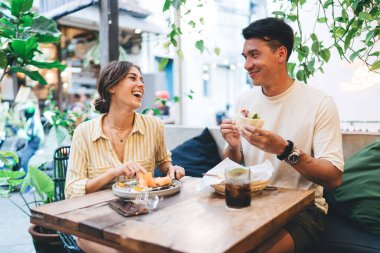 Modern kafeteryada yemek yerken ve yemek yerken birbirine bakan çok ırklı güzel bir çift.