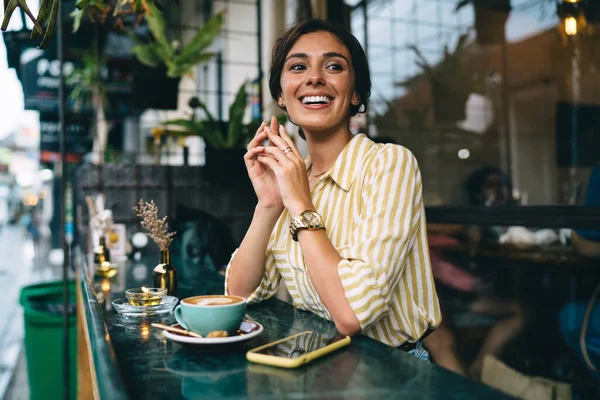 Munter Kvinne Uformelle Klær Sittende Ved Bordet Med Smarttelefon Kaffe – stockfoto