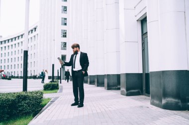 Tıraşsız, stil sahibi sağdıcın el ele durduğu ve büyük beyaz binanın yanındaki tablette düğün konuşması metninin üzerinden geçtiği yan manzara.