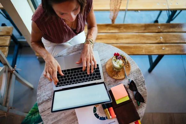 モックアップ画面でカフェのインテリアに座っている女性のフリーランスの作物のイメージは 研究のブラウザのウェブページを作る 女性はキーボードを入力してブログでメディアコンテンツを共有するための近代的な技術を使用して — ストック写真