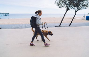 40 yaşında kadın, spor giyimli, spor ayakkabılı, sırt çantalı, tasmalı, sahil kenarındaki boş barajda gezen köpek tasmalı.
