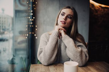 Düşünceli hippi kız, kafeteryanın penceresine kahve saatinde, Kafkasyalı kadın müşteri 20 yaşında, kafein içeceği aroması üzerine kafa yoruyor.