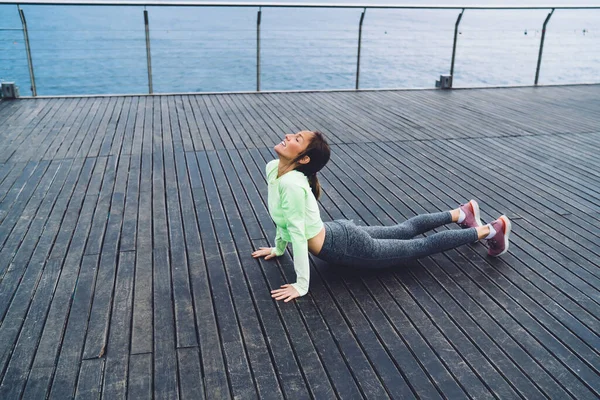 閉じた目でヨガの練習を楽しむ集中フィットの女の子で海岸桟橋に立ち 穏やかな女性は活力のレクリエーションを感じながら体と心を訓練しながらエネルギーインスピレーションを得る — ストック写真