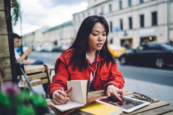 Estudante Étnica Concentrada Navegando Gadget Com Fones Ouvido Tomar Notas — Fotografia de Stock