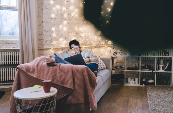 Cheerful Young Woman Glasses Sitting Sofa Using Netbook While Chatting — Stock Photo, Image