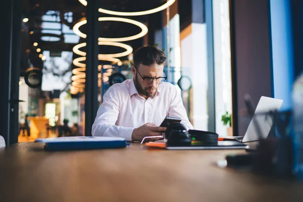 Mladistvý Freelancer Optických Brýlích Sedí Stolu Instalaci Obdržel Upozornění Smartphone — Stock fotografie