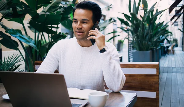 Content Ethnic Male Freelancer White Sweater Talking Mobile Phone While — Stock Photo, Image