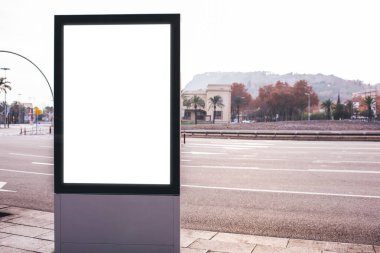 Geniş yolu ve büyük reklam panosu olan modern şehir dağın ve gökyüzünün yanındaki eski binaya karşı sisle kaplı.