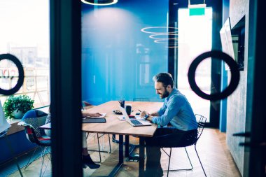 Gülümseyen erkek yöneticinin konferans masasında tanınmayan bir bayan meslektaşla oturup iş meselesini tartışırken dizüstü bilgisayar ekranına bakması.