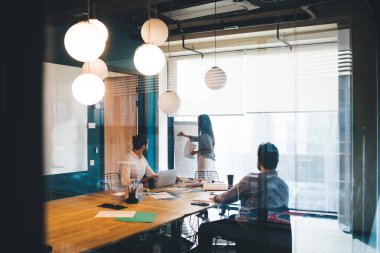 Beyaz tahtaya yazı yazarken ve modern yönetim kurulunda dizüstü bilgisayar kullanırken kadın ve erkek çalışanların istatistiksel araştırma yaptığı arka plan görüntüsü