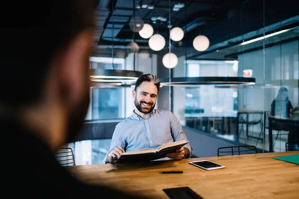 Hombre Moreno Barbudo Alegre Camisa Azul Sentado Mesa Con Libro —  Fotos de Stock