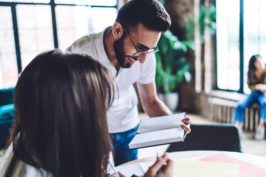 Genç çalışanlar kitaptaki notlarla ilgilenirken ve hataları tartışırken çağdaş işyerindeki raporlarda birlikte çalışırlar.