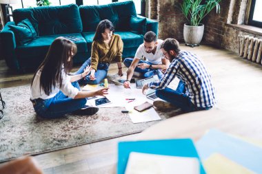 Moda dünyasından tam teşekküllü meslektaşlar, yerde oturup iş projelerini resmediyorlar.