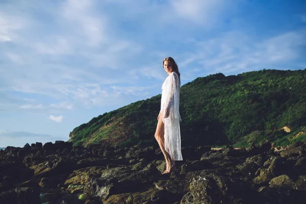 해변의 흰옷을 아름다운 여인이 자연계의 하늘을 배경으로 거칠거칠 위에서 — 스톡 사진