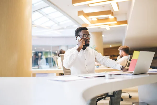 Afro Americano Masculino Óculos Falando Telefone Enquanto Sentado Mesa Com — Fotografia de Stock