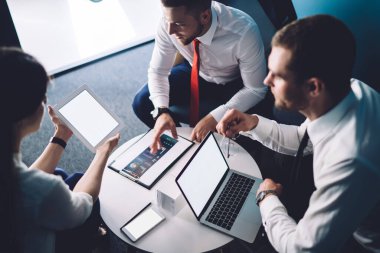 Çok ırklı çalışanlar resmi olarak iş konularını tartışırken ve yaratıcı çalışma alanlarında yuvarlak masa başında otururken aletler kullanırken giyiyorlar.