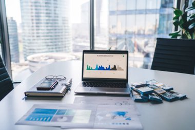 Ticaretle ilgili bilgi istatistiklerine sahip modern laptop bilgisayarı ekranda gösteriliyor. Şirket içi ofis masasında, netbook ve wat para konsepti olarak kalıyor.